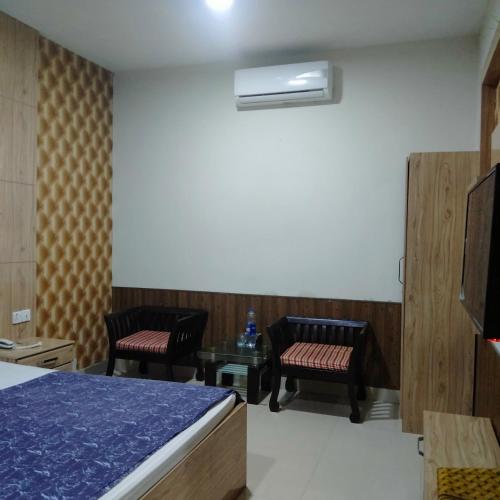 a room with two chairs and a bed and a tv at E- Town Guest House karachi in Karachi