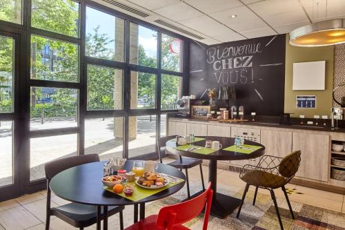 モンティニー・ル・ブルトンヌーにあるB&B HOTEL Saint-Quentin-en-Yvelines Centre Gare 4 étoilesのテーブル2台と椅子、窓のあるレストラン