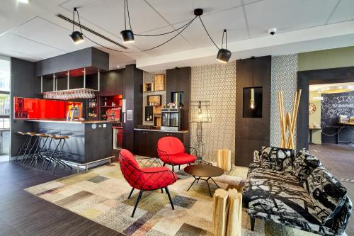 sala de estar con sillas rojas y cocina en B&B HOTEL Saint-Quentin-en-Yvelines Centre Gare 4 étoiles, en Montigny-le-Bretonneux