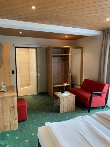 a hotel room with a bed and a red chair at Clubhotel Götzens in Innsbruck