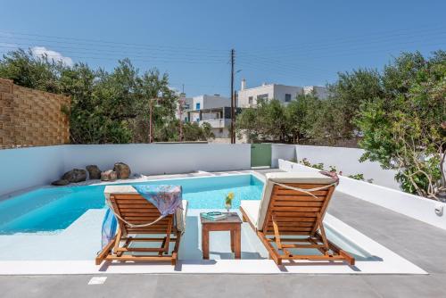 two chairs and a table next to a swimming pool at Terra Oliva Milos in Pollonia