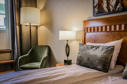 a hotel room with a bed and a green chair at First Hotel Millennium in Oslo