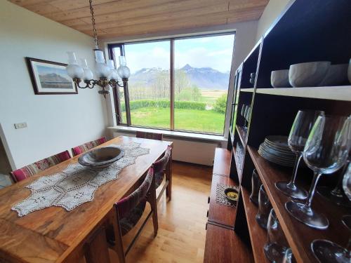 a dining room with a table and a large window at House with a magical garden and sunroom in Höfn