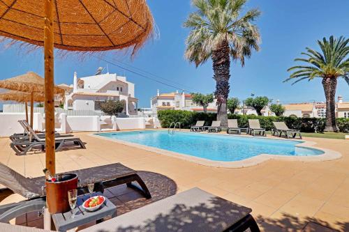 a pool with chairs and umbrellas and palm trees at Villux - Vila Enar-6 quartos, ideal para familias in Albufeira