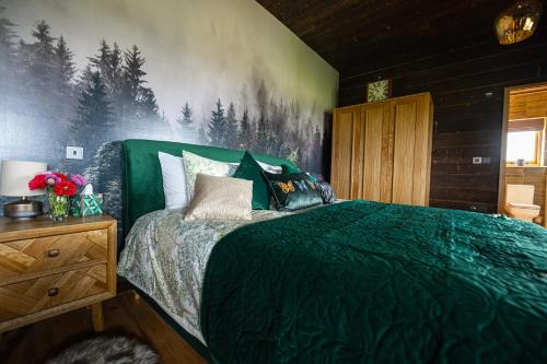 a bedroom with a bed with a green comforter at Luxury Log Cabin with a Hot Tub in Stone