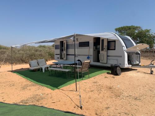 a caravan with a table and chairs and a tent at Caravans through the nature in Mikhmoret