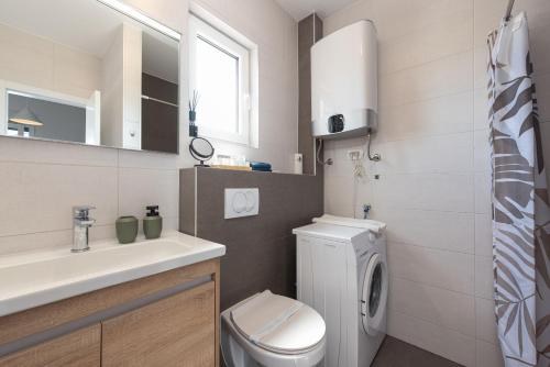 a bathroom with a toilet sink and a washing machine at Villa NiA ZadarVillas in Nin