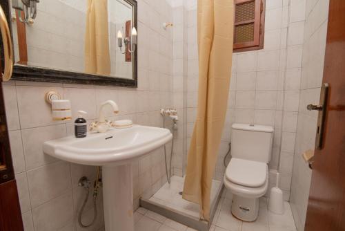 a white bathroom with a sink and a toilet at Ligres Beach - 2 Bedrooms Apartment Sea View in Agia Paraskevi