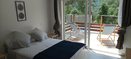 une chambre avec un lit et un balcon avec des chaises dans l'établissement Maison 38m2 15min de Corte 30min de Bastia, à Bigorno