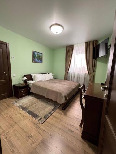 a bedroom with a bed and a table and a window at Spadok in Kamianets-Podilskyi