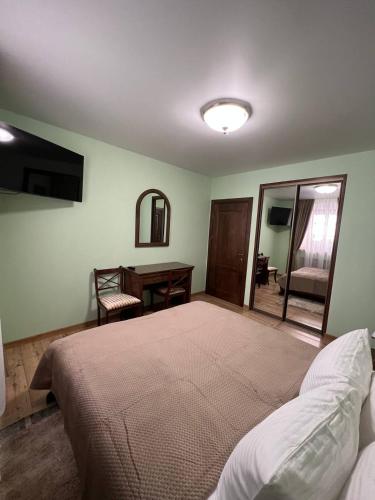 a bedroom with a large bed and a desk at Spadok in Kamianets-Podilskyi