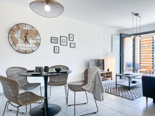 a dining room with a table and chairs and a clock at Le frère Charmes in Aurillac