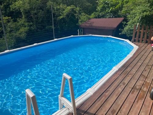 a large blue swimming pool on a wooden deck at Gîte La Fougère in Vals-les-Bains