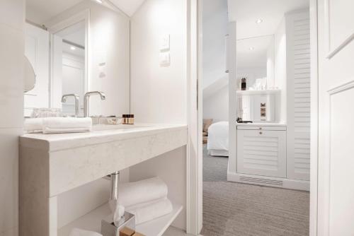 a white bathroom with a sink and a mirror at Riva Marina Hvar Hotel in Hvar