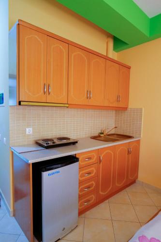 a kitchen with wooden cabinets and a black and white dishwasher at Vila Lida in Sarandë