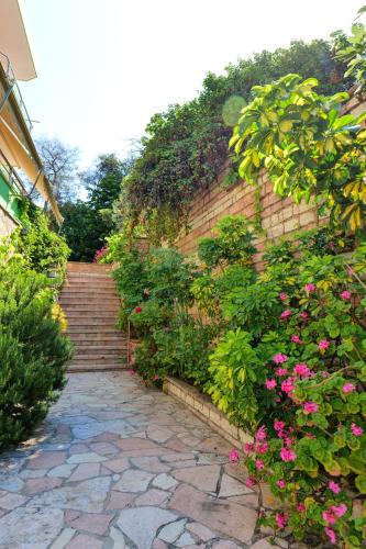 a stone walkway with pink flowers on a brick wall at Vila Lida in Sarandë