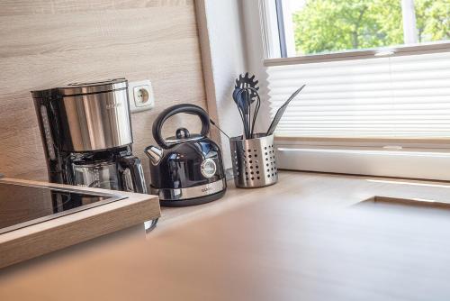 eine Küchentheke mit einer Kaffeekanne und einem Fenster in der Unterkunft 50137 "Deichkajüte 6" in Carolinensiel