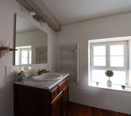 ein weißes Bad mit einem Waschbecken und einem Fenster in der Unterkunft Au Pont Vert in Fontaine-Française