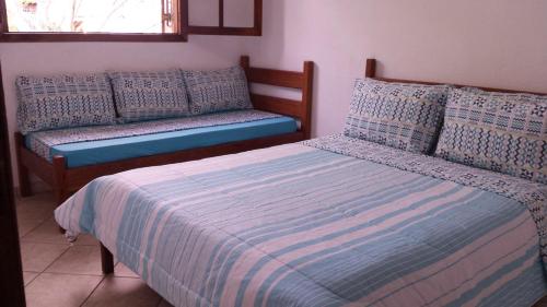 a bedroom with two beds with pillows and a bench at Chalés Ancoradouro in Boracéia