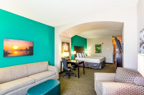 a hotel room with a couch and a bed at Baymont by Wyndham Andrews TX in Andrews