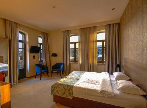 a hotel room with a bed and a desk and windows at Old Meidan Tbilisi By Urban Hotels in Tbilisi City