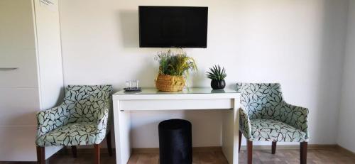 twee stoelen en een bureau met een televisie aan de muur bij Wait`N Sea House in Tuzla