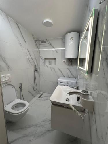 a white bathroom with a toilet and a sink at Luxury sea view duplex in Durrës
