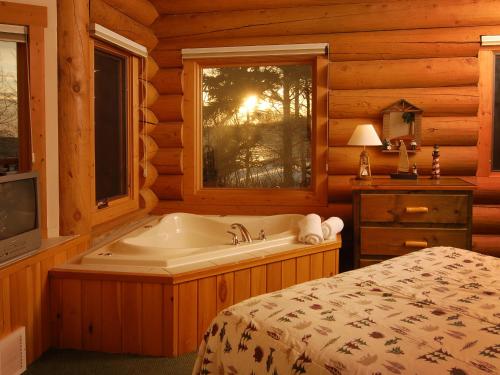 1 dormitorio con bañera, cama y ventana en Grand Superior Lodge, en Castle Danger