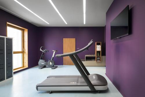 a gym with a treadmill and a purple wall at Okko Hotels Grenoble Jardin Hoche in Grenoble
