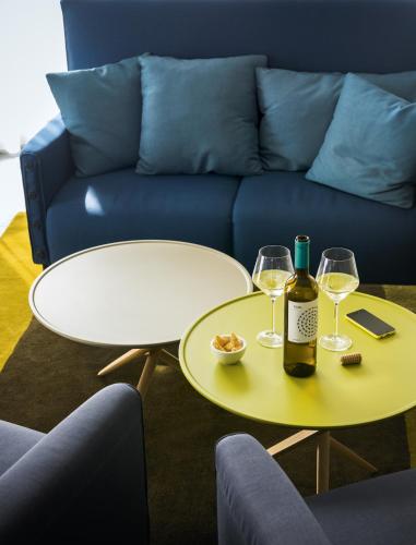 un canapé bleu avec deux tables avec des verres à vin dans l'établissement OKKO Hotels Grenoble Centre, à Grenoble