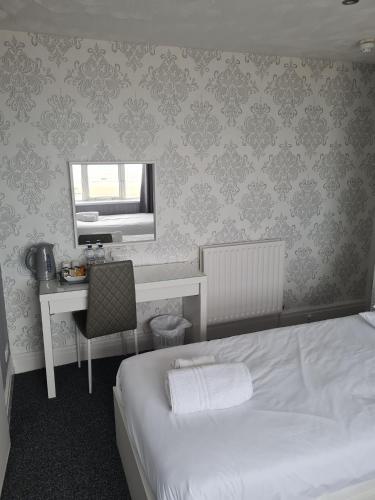 a bedroom with a bed and a desk and a mirror at Queens Plaza Hotel in Blackpool