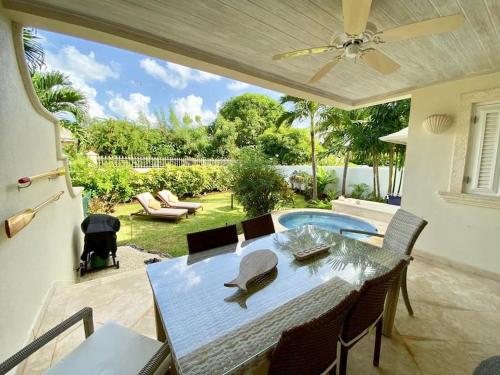 a patio with a table and chairs and a swimming pool at No5 Battaleys Mews Mullins Beach in Saint Peter