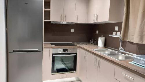 a kitchen with white cabinets and a sink and a stove at Aphrodite goddess in Artemida