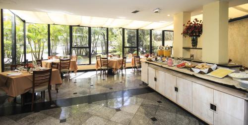 - un restaurant avec des tables, des chaises et de grandes fenêtres dans l'établissement Bienal Suítes, à São Paulo