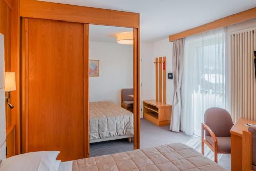 a hotel room with a bed and a mirror at Hotel Ladina in Campitello di Fassa