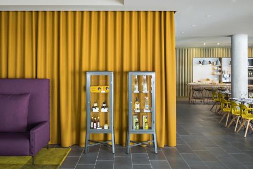 a restaurant with yellow curtains and a purple chair at Okko Hotels Grenoble Jardin Hoche in Grenoble