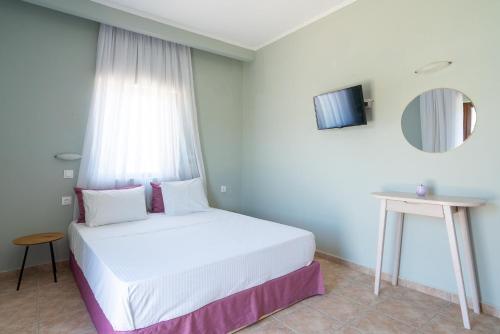 a white bed in a room with a window at Serenity Hideaway in Palaiochóra