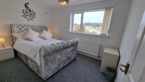 a bedroom with a bed with a chair and a window at Rozelle Villa in Ayr