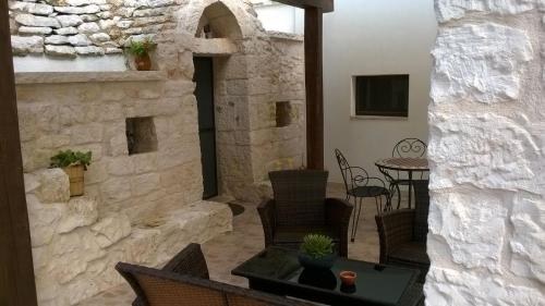 - un patio aux murs de pierre avec une table et des chaises dans l'établissement Al Trulletto, à Ceglie Messapica