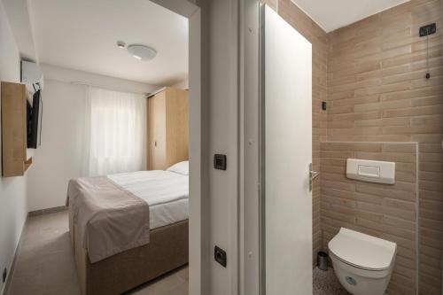 a small bathroom with a bed and a toilet at Hotel Delfin in Omišalj