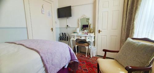 a bedroom with a bed and a desk and a mirror at Fleurie Guest House in Torquay