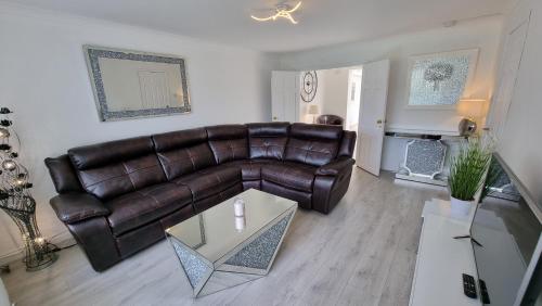 a living room with a leather couch and a table at Rozelle Villa in Ayr