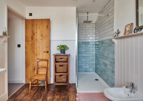 a bathroom with a shower and a sink and a chair at Luxurious property set in the heart of Cornwall with breathtaking views -Rhubarb Cottage in Helston