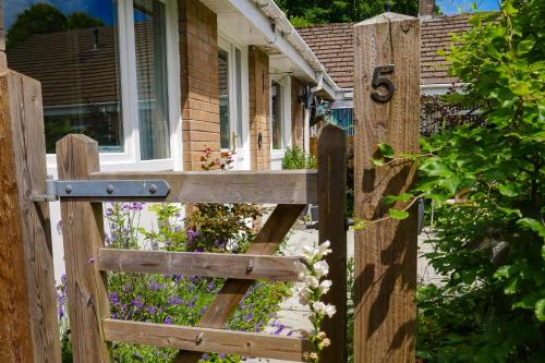 a wooden gate in front of a house with flowers at Waterfall Lodge in Pont-Nedd-Fechan