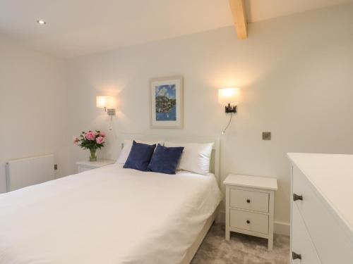 a bedroom with a white bed with blue pillows at Ferryside in Dartmouth