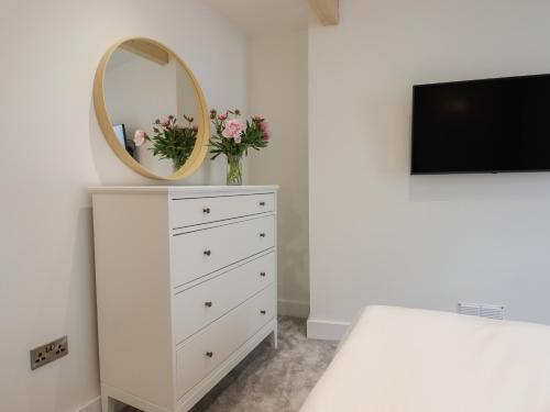 a white dresser with a mirror and a tv at Ferryside in Dartmouth