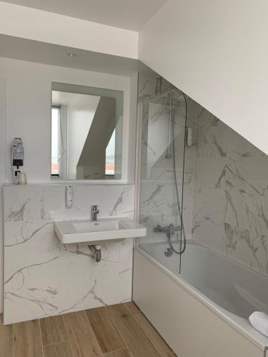 a white bathroom with a sink and a shower at Kyriad Crepy En Valois in Crépy-en-Valois