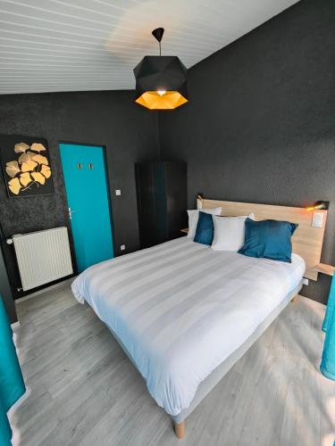 a bedroom with a large white bed with blue pillows at Gîte Le Petit Bambou in Bressuire