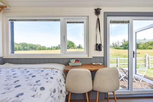 a bedroom with a bed and two chairs and windows at Crabden Shepherd Hut - Blendworth in Waterlooville