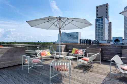 een patio met stoelen en een parasol op een dak bij aletto Hotel Kudamm in Berlijn